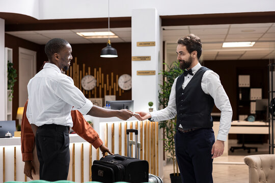 Cash tips are handed to bellboy for luxury concierge service after assistance with suitcases, showing gratitude and hospitality tipping culture.