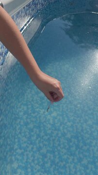 Person dipping pool water ph test strip