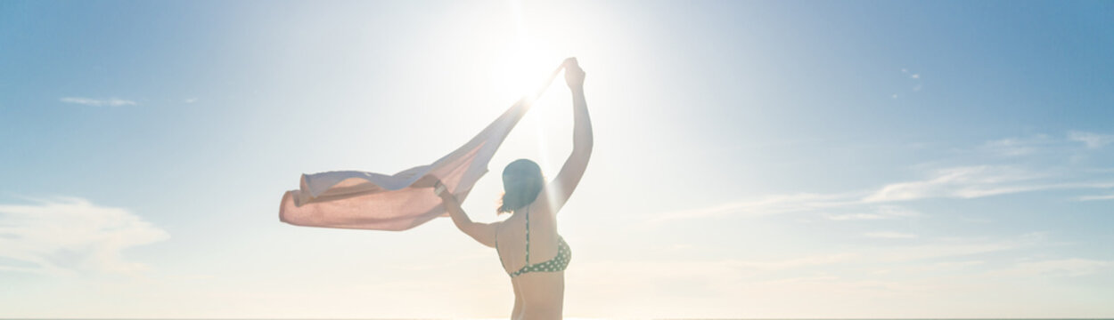 Woman standing with towel on the beach with ocean on background