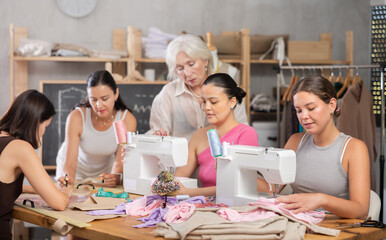Obraz premium Group of women of different ages sew and draw pattern on paper during sewing master class