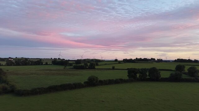 4K Aerial View of Green Farmland Beneath Colorful Evening Sky