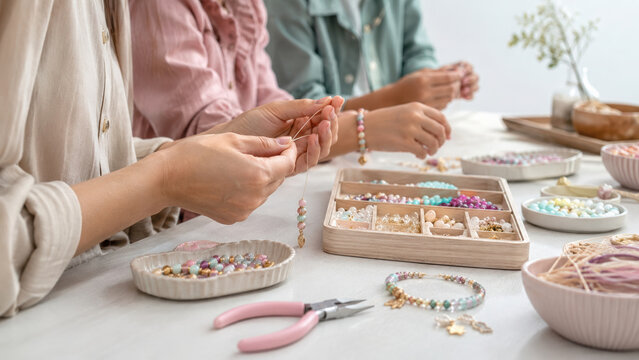 Workshop activity with family making colorful beaded jewelry together, creating bracelets and necklaces in bright creative space