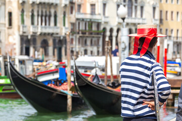 Gondolier standing next to gondola waiting for a client in Venice Italy © Maria