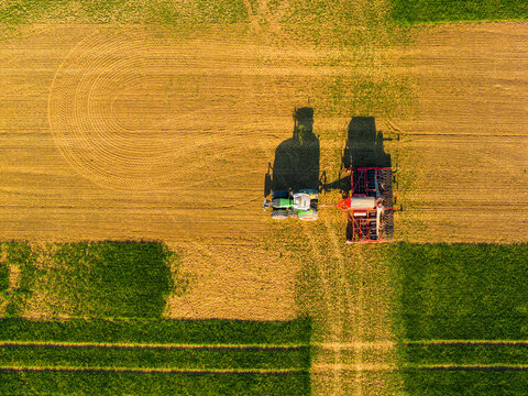 Aerial view of a tractor with a seed drill working in a cultivated field, creating distinct patterns in the soil under golden hour light. Chvalkovice, Hradec Kralove Region, Czechia.
