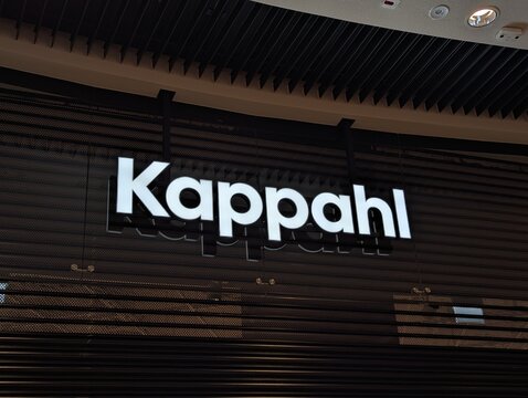 Warsaw, Poland,May 03, 2026. Bright white corporate Kappahl clothing brand storefront logo sign on a dark textured wood paneled wall surface. High quality photograph.