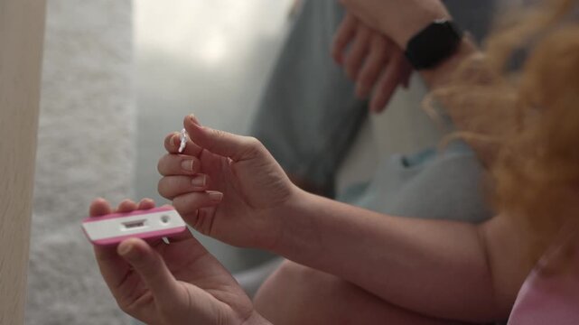 Woman applying dropper to pregnancy test at home