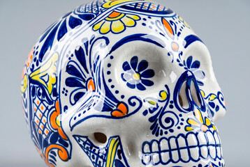 Fototapeta premium Ornate ceramic sugar skull with blue floral painting traditional Mexican Day of the Dead decoration close up [copy space]