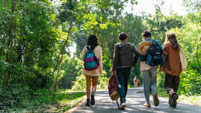 Group of Generation z people friends hiking through forest trail exploring nature together during eco travel adventure enjoying outdoor recreation sustainable tourism and healthy active lifestyle