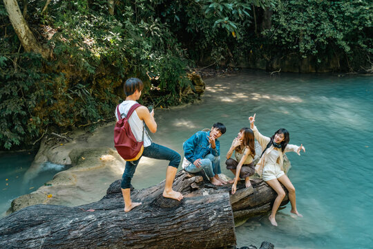  Young Asian man and woman friends using smartphone taking picture together at tropical forest enjoying eco tourism adventure outdoor travel active lifestyle nature therapy on summer holiday vacation.