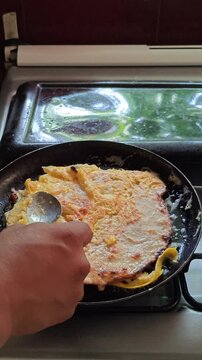 Cooking egg omelet in a frying pan on a stove