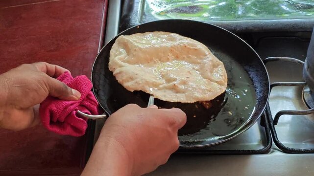 Cook attempting to flip crispy tortilla frying in boiling oil