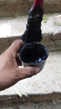 Person cleaning paint residue from brush using solvent thinner