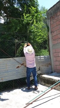 Worker removing tied galvanized wire from chain link fence mesh
