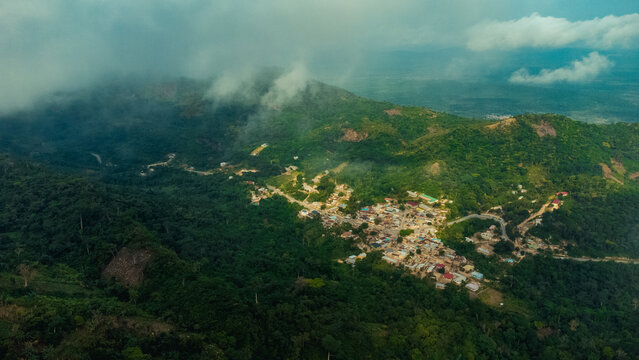 Aerial view of Mt. Gemi and the village of Amedzofe nestled among lush green mountains with clouds and winding roads in Amedzofe, Volta Region, Ghana.