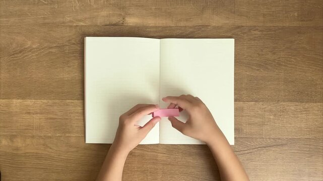 Child's Hands Peel a Pink Sticky Note and Press It onto a Lined Notebook, 4K