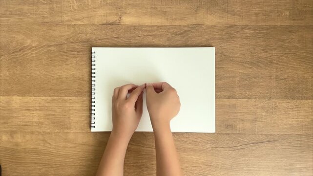 Child's Hands Press a Dusty Pink Heart Sticker onto a White Notebook, 4K