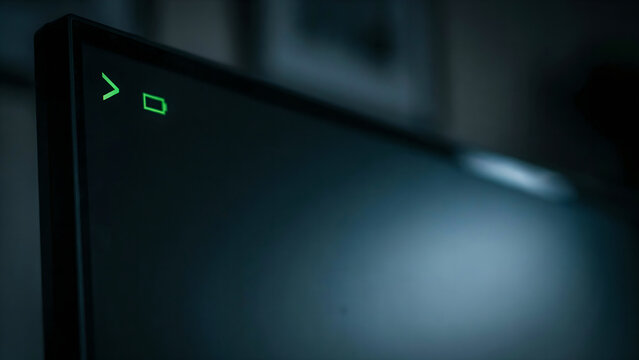 Closeup of a computer monitor screen displaying a glowing green command prompt and a battery icon in the corner