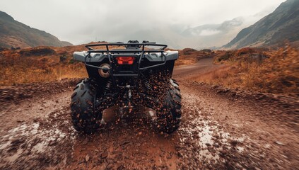 Naklejka premium Low-angle shot of a 4x4 ATV on a gravel road in autumn at a misty mountain. Off-road vehicle adventure concept. Quad bike hire.