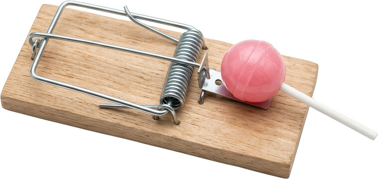 A pink lollipop is placed as bait on a wooden mousetrap with a metal spring mechanism highlighting a deceptive lure candy sweet deception danger risk temptation sugar caught