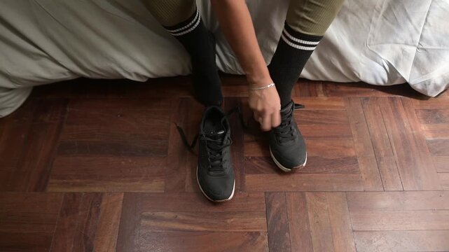 Fit woman preparing for workout tying sneaker shoelaces