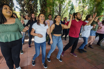 Fototapeta premium Group of latino friends enjoying a salsa dancing class outdoors in Mexico Latin America. Hispanic people moving to the rhythm and having a fun together