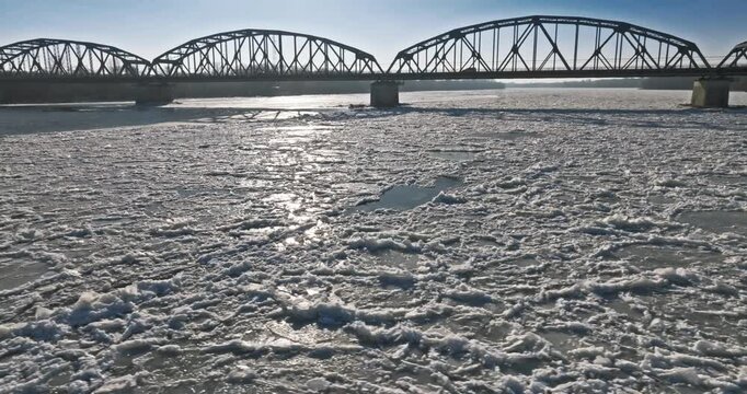 Bridge with traffic over a frozen river with ice floes.