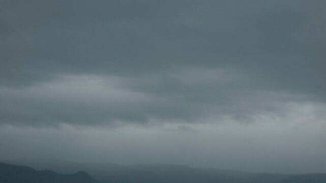 Silhouette of distant mountain ranges and gray clouds
