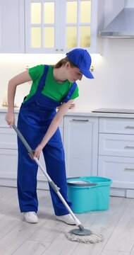 Teenage worker mopping floor in kitchen. Part-time job