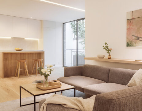 A close-up of a very modern living room featuring simple, concealed modern lighting and floral accents; the new furniture avoids a futuristic look, complementing the open-plan layout shared with the k