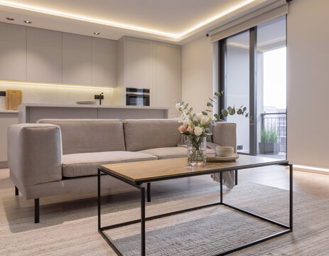 A close-up of a very modern living room featuring simple, concealed modern lighting and floral accents; the new furniture avoids a futuristic look, complementing the open-plan layout shared with the k