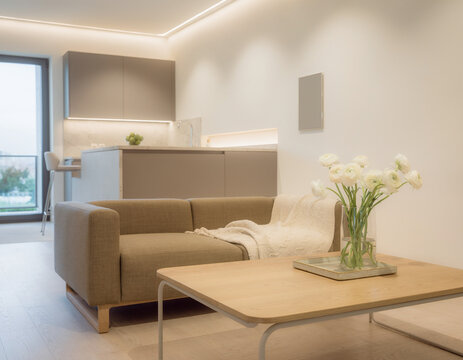 A close-up of a very modern living room featuring simple, concealed modern lighting and floral accents; the new furniture avoids a futuristic look, complementing the open-plan layout shared with the k