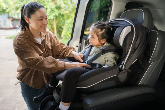 mother is fastening safety belt to preschool child girl in car seat, safety baby chair travelling