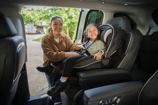 mother is fastening safety belt to preschool child girl in car seat, safety baby chair travelling