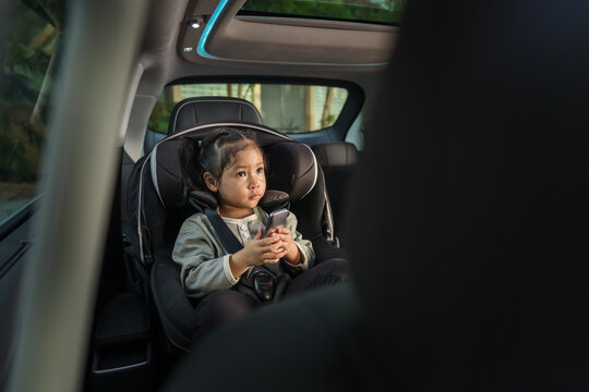 preschool child girl watching rear entertainment screen or ceiling screen while sitting in car seat, safety baby chair travelling