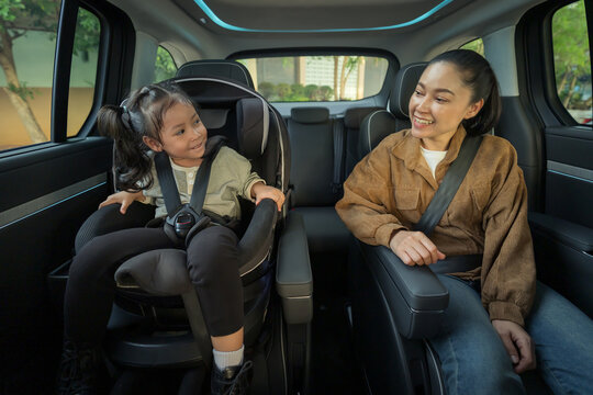 happy mother take care her preschool girl in car seat. play and talking with child