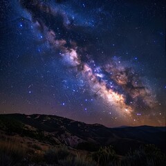 Fototapeta premium The Milky Way galaxy arcs majestically over a dark, mountainous landscape under a starry night sky.