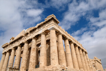 Fototapeta premium ancient Parthenon stands tall under a blue sky in Athens, Greece during midday with clouds in the background.