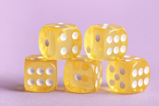 Yellow game dices on lilac background
