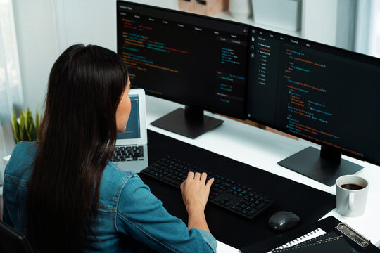 Young Asian in IT developer creating with typing online information on pc with coding program data of website application, wearing jeans shirt. surrounded by safety analysis two screens. Stratagem.