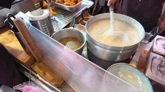 Street Vendor Stirring Large Pot of Boiling Rice Congee in Bangkok