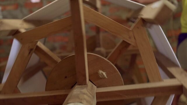 Wooden yarn swift spinning to wind fabric material in textile workshop.