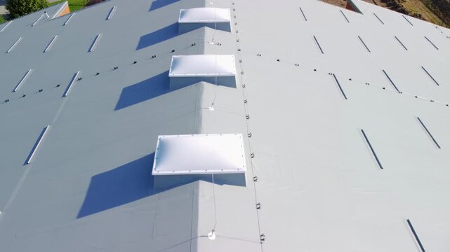 Aerial view of modern warehouse grey roof surface with skylights and lightning protection system.