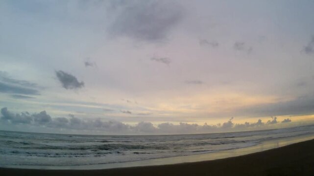 Cinematic ocean waves on a tropical beach at sunset, dramatic sky with purple and yellow clouds, calm horizon landscape background 4k.