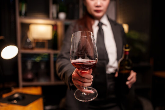 Bartender Woman is holding a glass of red wine on the bar counter.