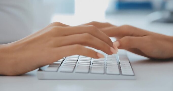 Close up motion of hands typing on computer keyboard working on office desk.
