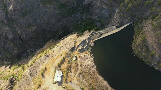 Majestic aerial perspective of the DelMulato Dam, a crucial water reservoir nestled within the dramatic and rugged Mogan ravine on Gran Canaria