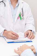 Doctor and patient having a medical consultation for green and pink ribbon to patient for concept...