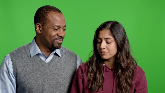 Concerned father talks to his teenage daughter against a green screen background. Communication, parenting, and family dynamics in a supportive and emotive studio environment.