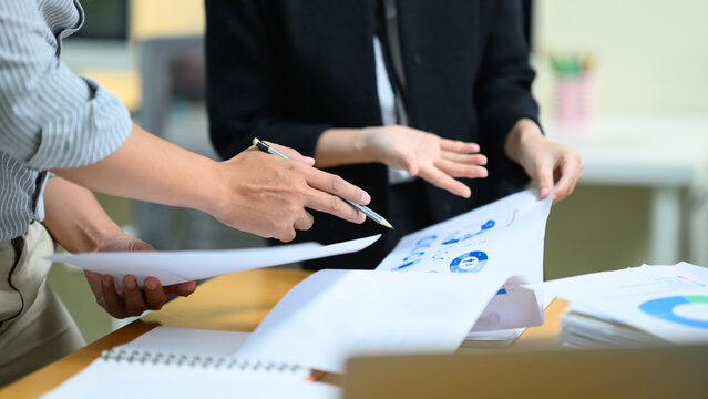 Business Audit Meeting with Two Professionals Reviewing Financial Charts and Documents at Office Desk