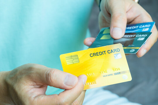 Close up of hand human holding multiple color credit cards, choosing a red card for payment, concept of consumerism, financial management, debt and cashless society and saving money